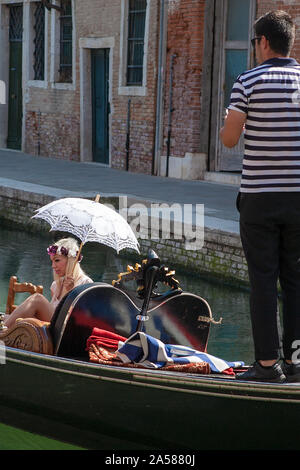 Gondola con glamour del biondino di passeggero in possesso di un ombrellone, Rio del Malcanton, Santa Croce, Venezia, Italia Foto Stock