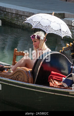 Gondola con glamour del biondino di passeggero in possesso di un ombrellone, Rio del Malcanton, Santa Croce, Venezia, Italia Foto Stock