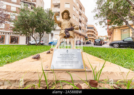 Dona Passant Nyores in Guardamar del Segura, Spagna, Europa. Resina e la scultura di sabbia di donna che fa una striscia di dolci secchi peperoncino. Agricoltura Foto Stock