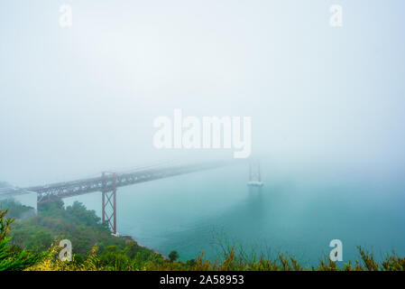 Vista su nebbia a Ponte 25 de Abril è una sospensione ponte che attraversa il fiume Tejo, Portogallo Foto Stock