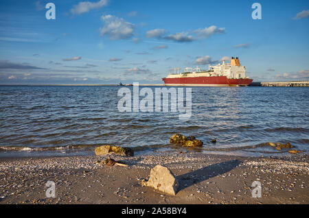 Spiaggia con LNG in distanza al tramonto a Swinoujscie, Polonia. Foto Stock