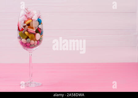 Bicchiere di vino pieno di caramelle colorate. Foto Stock