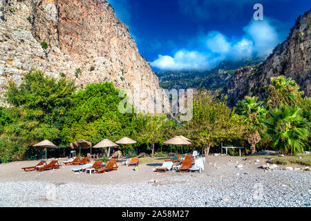 Sedie a sdraio e ombrelloni di paglia sulla spiaggia nella Valle delle Farfalle, Riviera Turca, Turchia Foto Stock