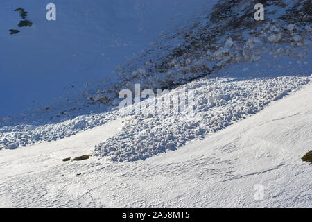 Piccolo neve bagnata a valanga detriti nelle montagne di Bucegi, Romania, su un Nord versante affacciato nel tardo pomeriggio, inizio primavera - close up. Foto Stock