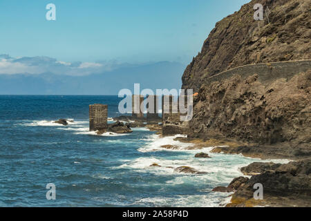 Vista dell'isola di Tenerife da Santa Catalina beach. Enormi pilastri di calcestruzzo per gru e le rovine della vecchia Hermigua porta. La Gomera Canarie, Isla Foto Stock