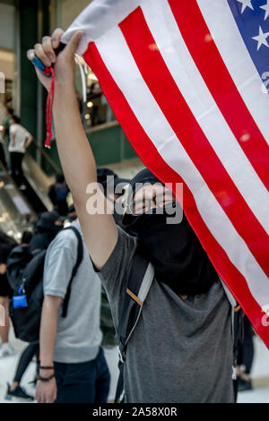 Hong Kong contestatori wave inglesi e americani le bandiere in segno di protesta in un centro commerciale per lo shopping di Hong Kong prima di violenza erutta Foto Stock