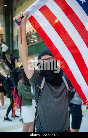 Hong Kong contestatori wave inglesi e americani le bandiere in segno di protesta in un centro commerciale per lo shopping di Hong Kong prima di violenza erutta Foto Stock