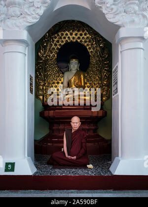 YANGON, MYANMAR - CIRCA NEL DICEMBRE 2017: Monk meditando alla Shwedagon pagoda di Yangon Foto Stock