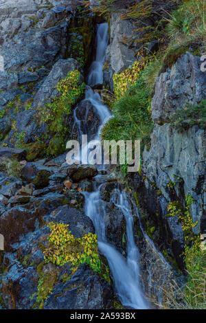 La cascata nel bosco con alberi colorati durante la stagione autunnale Foto Stock