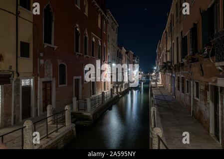 Immagine orizzontale di un canale tra gli edifici di appartamenti durante la notte a Venezia, Italia Foto Stock