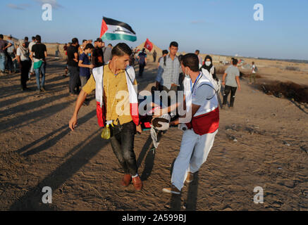 La striscia di Gaza, la Palestina. Xviii oct, 2019. I medici palestinesi trasportare una persona infortunata durante un anti-Israele dimostrazione per chiedere la fine di anni di assedio su Gaza sul confine Israel-Gaza nel sud della striscia di Gaza. Credito: SOPA Immagini limitata/Alamy Live News Foto Stock