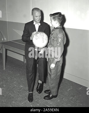 Il mercurio astronauta John Glenn tenendo un globo mentre si parla con il ragazzo di un boy scout o cub scout. Foto Stock