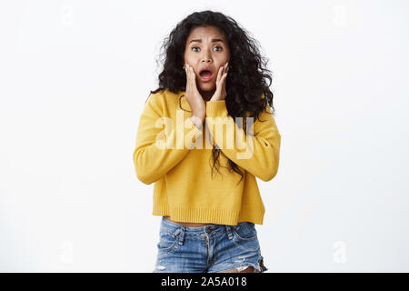 Scioccato e allarmato, preoccupati, curly-haired americano africano donna in felpa gialla affannosa spaventata, accigliata dicendo watch-out come sensazione di paura Foto Stock
