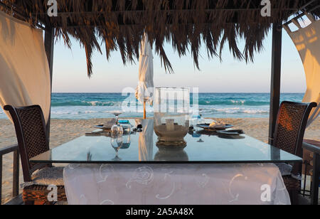 Gazebo sulla spiaggia con la tabella set. Candela sul tavolo. Contesto rilassante. Nessuno sulla spiaggia. Mare blu sul retro. Vacanza fantastica Foto Stock