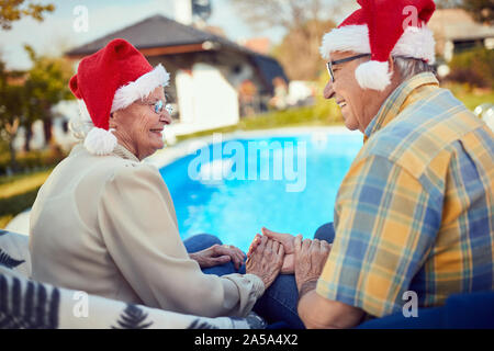 Senior Coppia sorridente in cappelli di Babbo Natale festeggiano il Natale Foto Stock