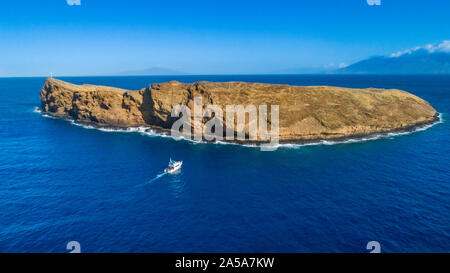 Molokini cratere, antenna shot della parete posteriore della forma di una mezzaluna isolotto con una carta di immersione barca si avvicina, Maui, Hawaii. Foto Stock