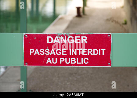 Close-up di un cartello di avviso su un cancello verde, in Paris-France, nei pressi di un canale. 'Drabbia passaggio interdit au public" o "pericolo vietato immettere' Foto Stock