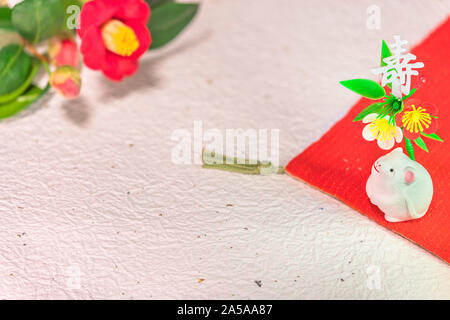 Un giapponese di biglietto di auguri con un fiore di Tsubaki chiamato anche il winter rose e un simpatico figurina di ratto per l'anno 2020 del mouse su un panno rosso decor Foto Stock