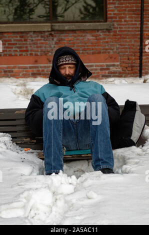 Un senzatetto uomo seduto su una panchina con un glumy umore. Il momento in cui la foto è stata scattata la temperatura esterna era -24 gradi centigradi. Montreal, Quebec Foto Stock