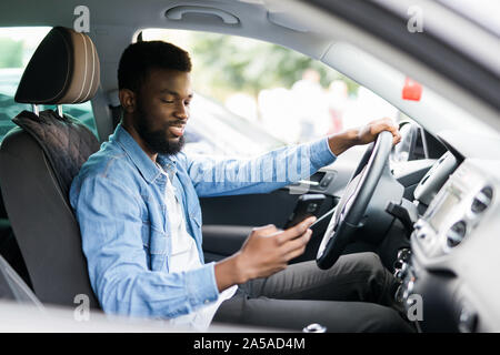 In auto vista del giovane maschio americano africano tenendo il suo telefono Foto Stock