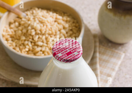 Fresco il latte parzialmente scremato in un vetro riciclabile flacone fornito alla porta passo per un latte tradizionale uomo Foto Stock