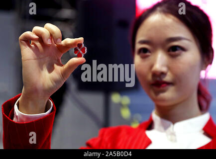 Shanghai, Cina. Xix oct, 2019. Un volontario visualizza un quattro-foglia di trifoglio-pulsante sagomato di volontari' uniforme al National Exhibition and Convention Center a Shanghai in Cina orientale, Ott. 19, 2019. Oltre 5.800 persone hanno giurato come volontari e siamo andati sul dovere di sabato per il prossimo secondo il China International Import Expo (CIIE), secondo la Shanghai comitato comunale della Gioventù Comunista della Cina. Credito: Liu Ying/Xinhua/Alamy Live News Foto Stock