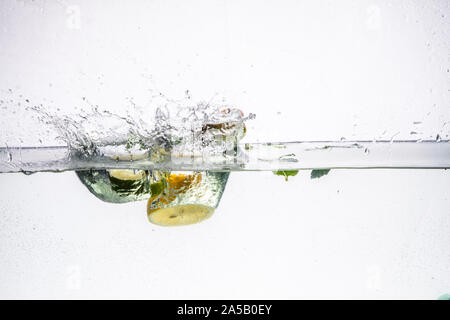 Un background di formazione di bolle in acqua blu dopo la frutta viene fatta cadere in esso. Foto Stock