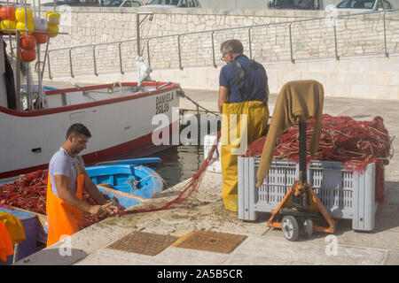 Fischer bei der Arbeit im Hafen von Tricase Porto, Lecce Apulien, Italien | pescatori al lavoro al porto di pesca di Tricase Porto, Lecce, Puglia, Italia Foto Stock