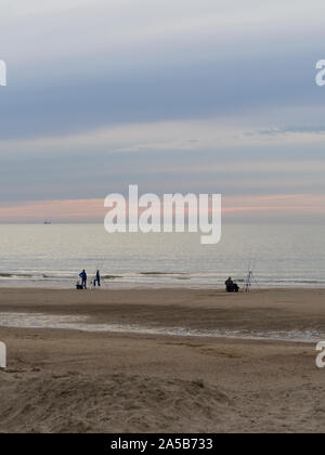 I pescatori nel crepuscolo della sera presso la spiaggia di Katwijk, Paesi Bassi. Foto Stock