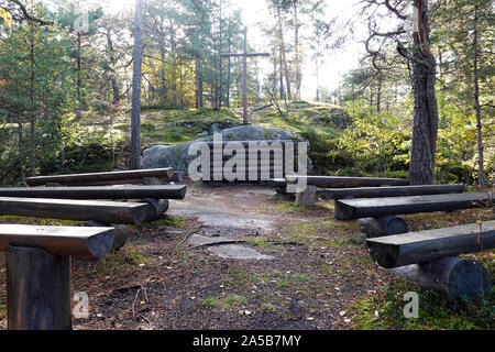 Semplice chiesa di foresta. Panche in legno e altare. Sole illumina il luogo santo dietro la croce. Foto Stock