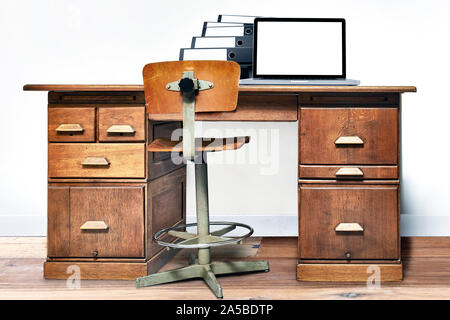 Laptop e cartella giacente su un vintage scrivania in una stanza con pavimento in legno Foto Stock
