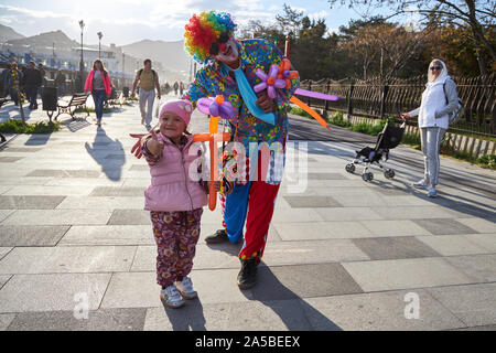 Sudak, Russia, Maggio 02, 2019: Clown in luminosi multi-vestiti colorati ha dato il simpatico bambino un palloncino fiore Foto Stock