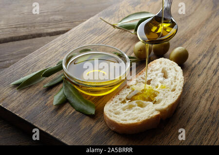 Fetta di pane condito con olio di oliva su sfondo di legno Foto Stock