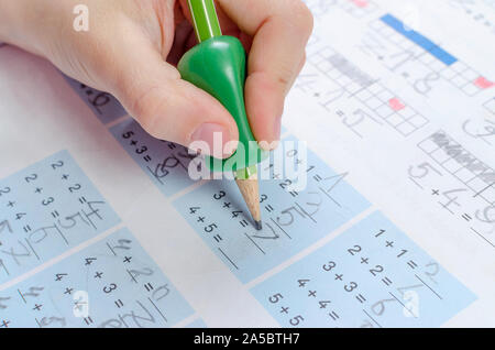 Bambino la mano con strumento di scrittura per aiutare da imperfetta tenuta della matita, closeup, homewortk, matematica Foto Stock