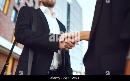 Business di handshake. Imprenditore e business donna fanno strette di mano mentre in piedi all'aperto Foto Stock