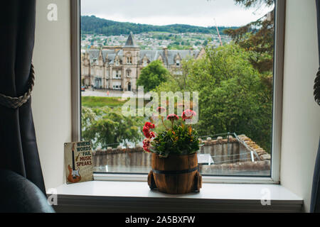 Guardando fuori una finestra di hotel a Inverness, Scotland. Un impianto di POT si siede sul davanzale, mentre altri edifici dal 1870 sono visibili in background Foto Stock