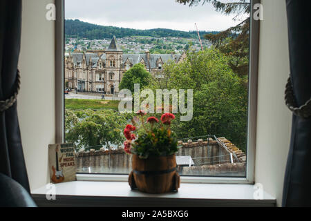 Guardando fuori una finestra di hotel a Inverness, Scotland. Un impianto di POT si siede sul davanzale, mentre altri edifici dal 1870 sono visibili in background Foto Stock