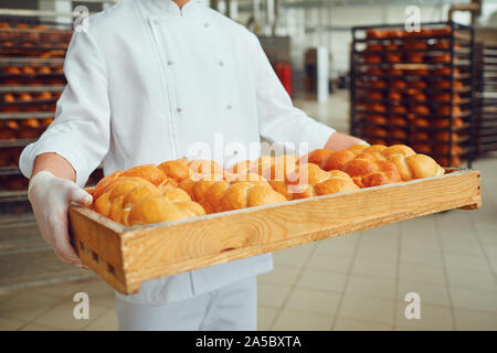 Baker con le mani in mano in attesa di un vassoio con pane fresco. Concetto di panetteria. Foto Stock