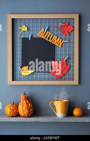 Griglia della foto con bordo rosso e arancio carta Foglie di autunno e il testo "Autunno". Tazza di tè e autunno decorazioni su un ripiano. Fall-relative mockup per il vostro Foto Stock