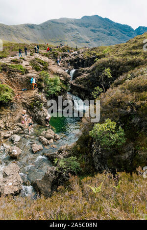 I turisti nuotare e scavalcare le cascate e rocce alla fata piscine, una famosa attrazione turistica dell'Isola di Skye in Scozia Foto Stock