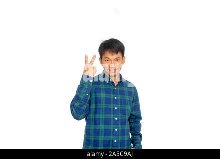 L'Asian disordinato uomo in blu plaid shirt è che puntano a due dita per il sovraccarico dello spazio vuoto in studio con la sua mano. Foto Stock