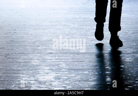 Sfocata ombra silhouette di una persona che cammina nella notte, dettaglio delle gambe Foto Stock