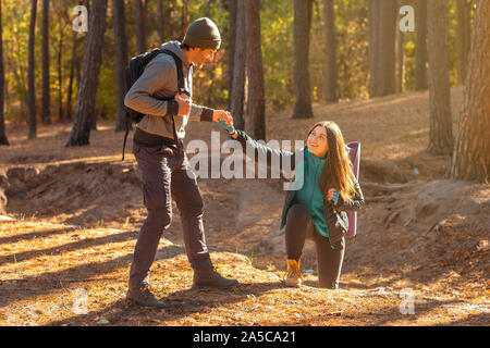 Bello escursionista aiutare la sua ragazza in salita in campagna Foto Stock
