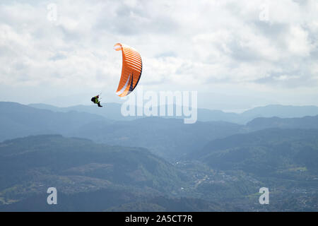 Parapendio sulle montagne. Uno arancione parapendio in Norvegia a Bergen in background e un cielo nuvoloso. Foto Stock