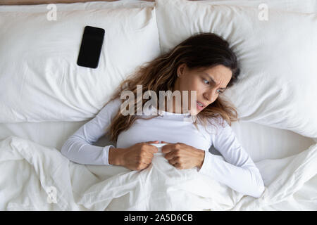 Irritato la millenaria razza mista donna risveglio dopo cellphone allarme. Foto Stock