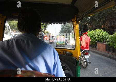 Un driver non identificato è a cavallo di un auto rickshaw attraverso le strade affollate di Jaipur. Foto Stock