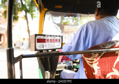 Un driver non identificato è a cavallo di un auto rickshaw attraverso le strade affollate di Jaipur. Foto Stock