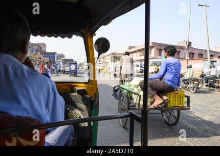 Un driver non identificato è a cavallo di un auto rickshaw attraverso le strade affollate di Jaipur. Foto Stock