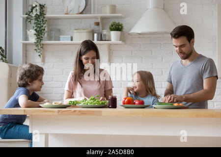 Genitori felici con il figlio e la figlia la preparazione della cena, chat Foto Stock