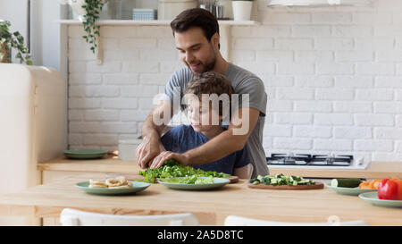 Padre amorevole insegnamento piccolo figlio di utilizzo superiore del coltello in cucina Foto Stock